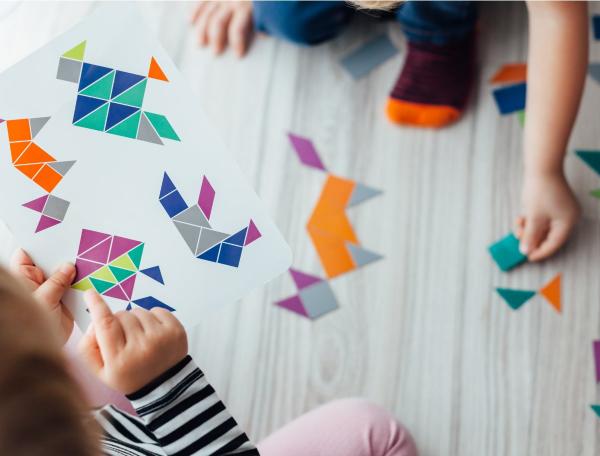 Small children arranging paper shapes on floor