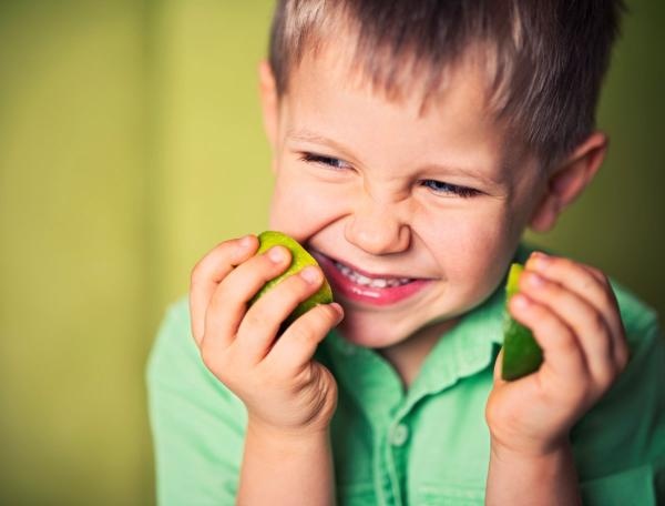 Boy holding halves of lime fruit in hands