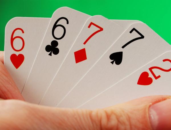 Hands holding up five playing cards 
