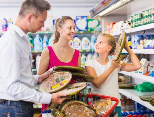 Father, mother and daughter looking at pizzas on shelf in store