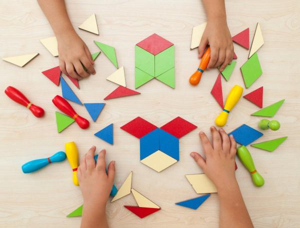 Children's hands playing with coloured 3d shapes