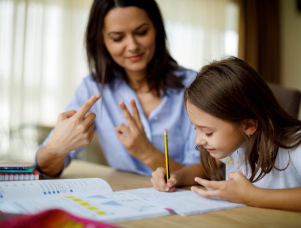 Mother and daughter counting with their fingers as daughter writes in notepad