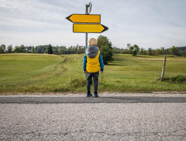 Child standing near road sign